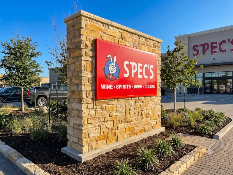 Large stacked stone signage wall with Spec's commercial sign at retail store entrance