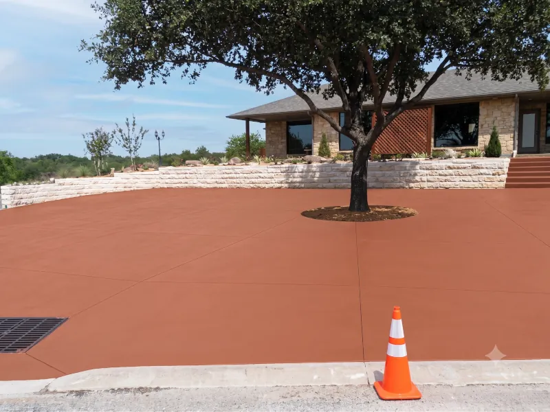 Residential property with terracotta stained concrete driveway and stacked stone retaining wall